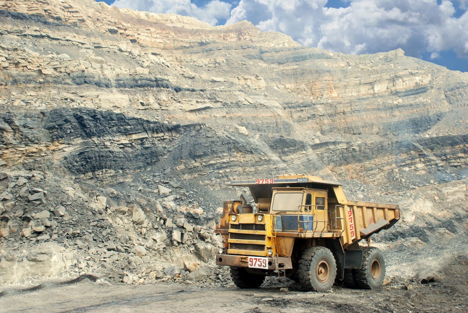 Large mining dump truck operating in an open-pit mine with layered rock walls