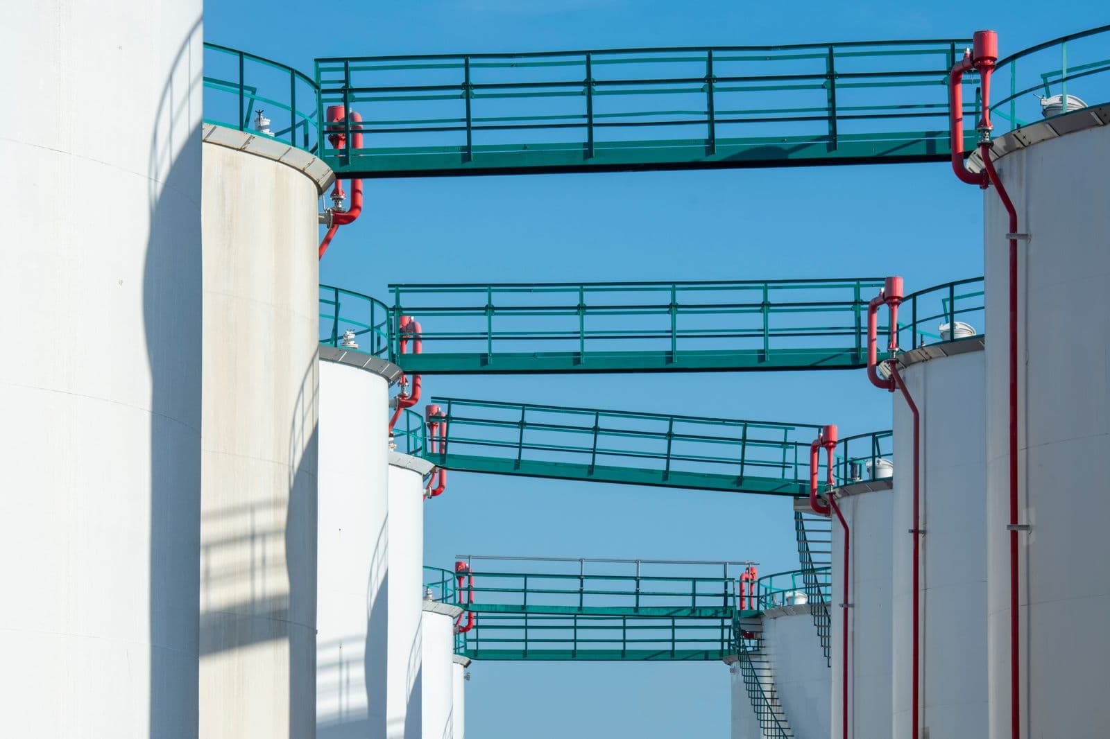 Industrial petroleum storage tanks with safety walkways and piping at a fuel terminal