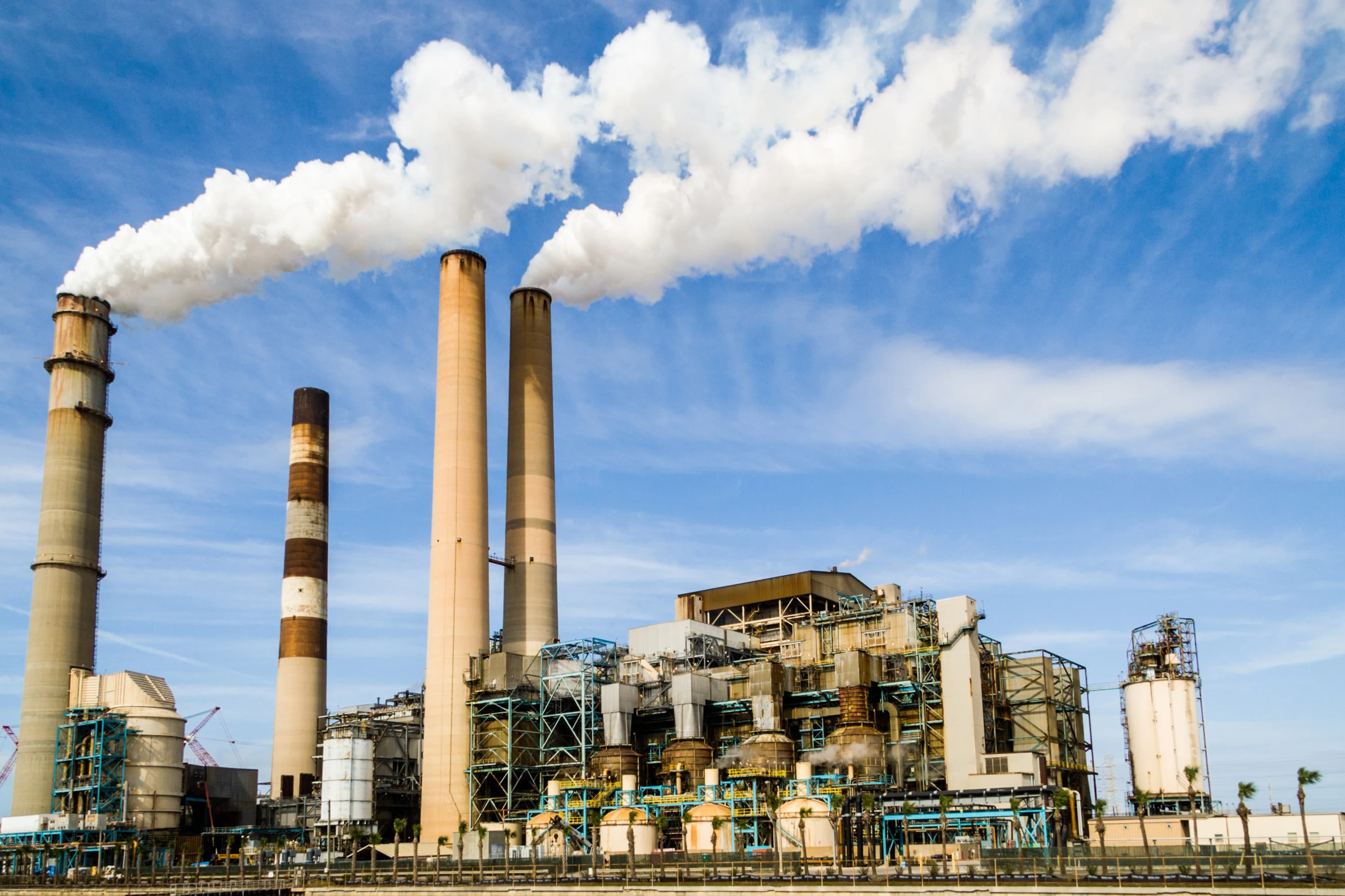 Industrial chemical processing facility with towers and piping: the type of plant where high-viscosity adhesives and sealants are manufactured