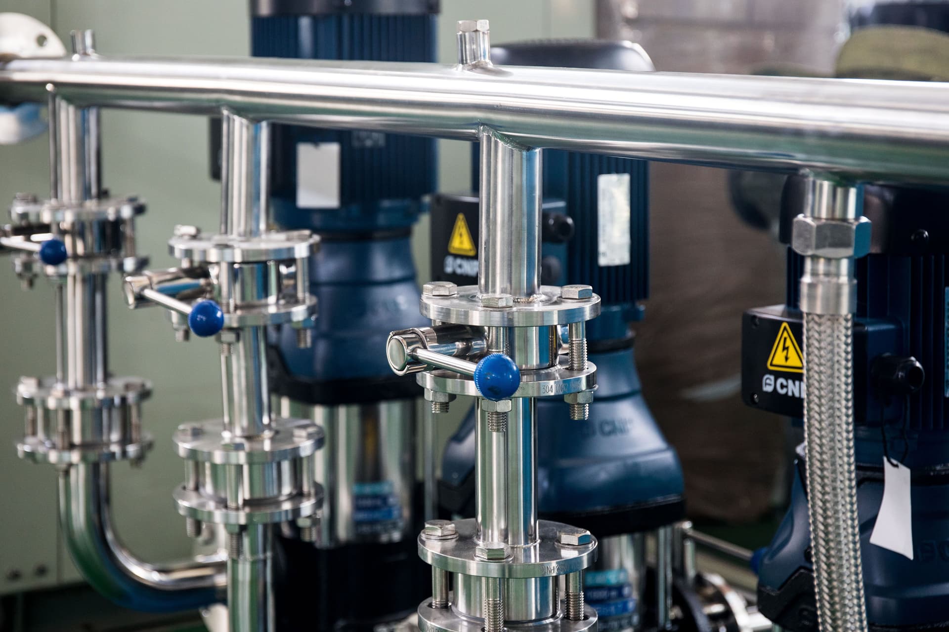 Stainless steel pump manifold with multi-stage vertical pumps and valve assemblies in an industrial fluid system