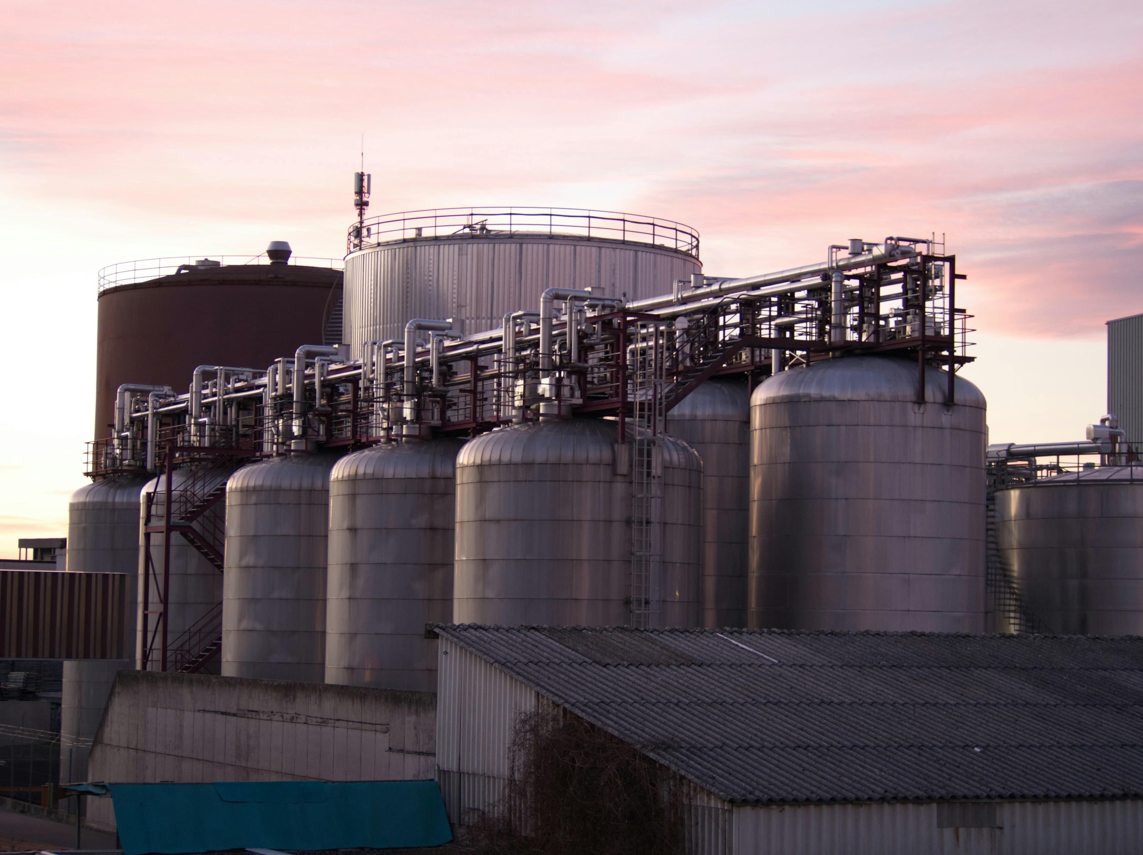 Stainless steel industrial storage tanks with interconnected piping at a processing facility